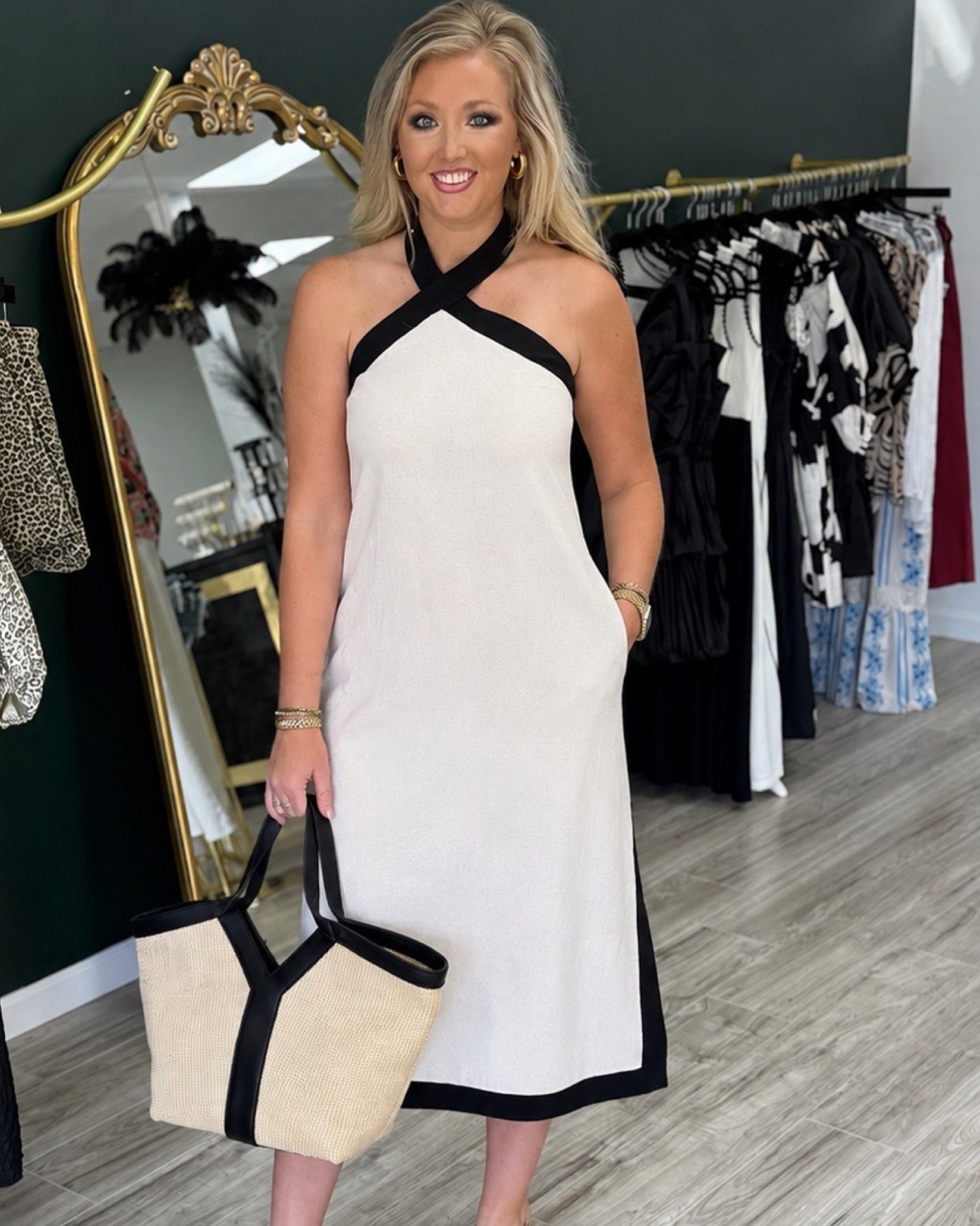 Woman in a white dress with black accents standing in a clothing store.