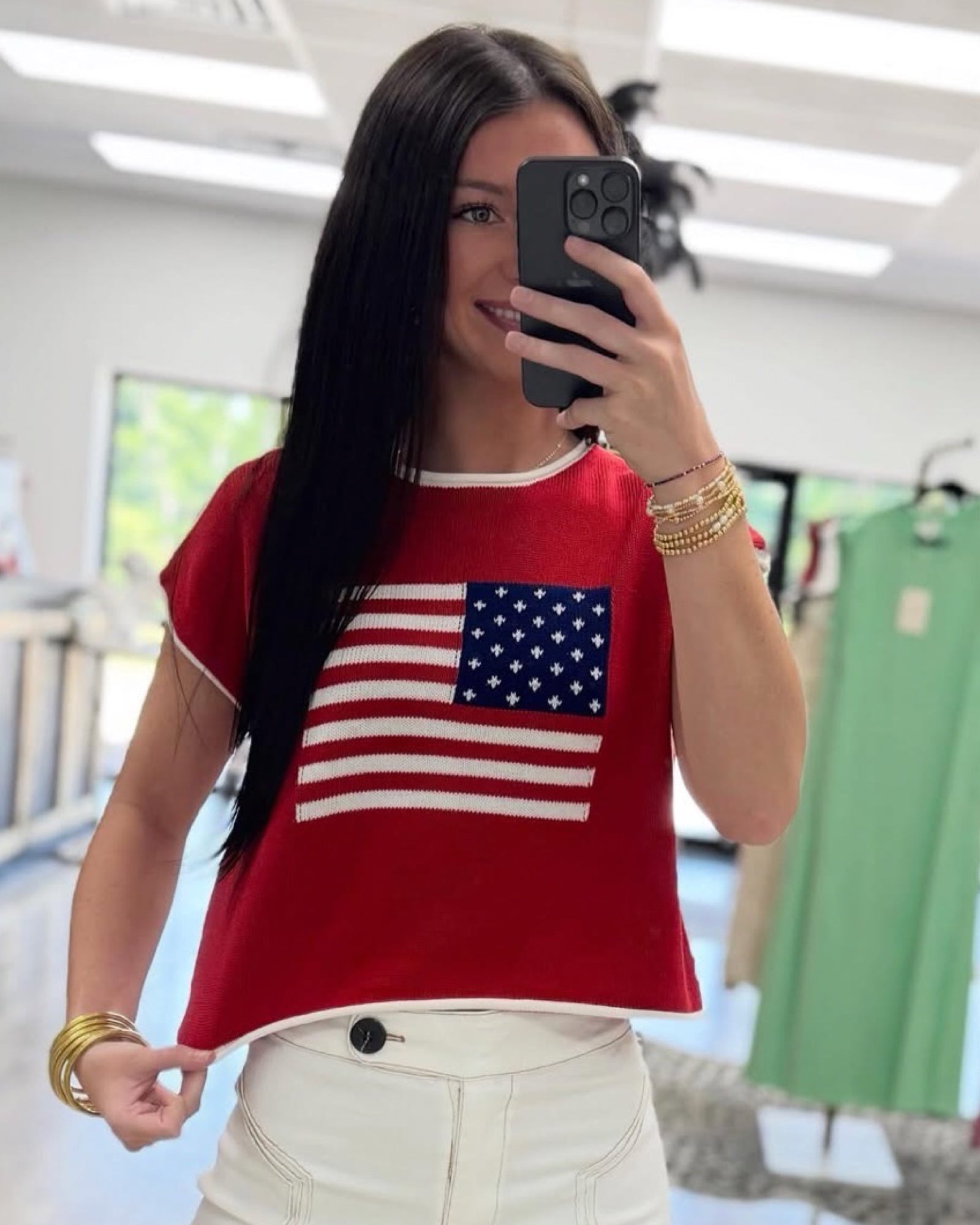 Person wearing a red shirt with an American flag design, taking a mirror selfie.