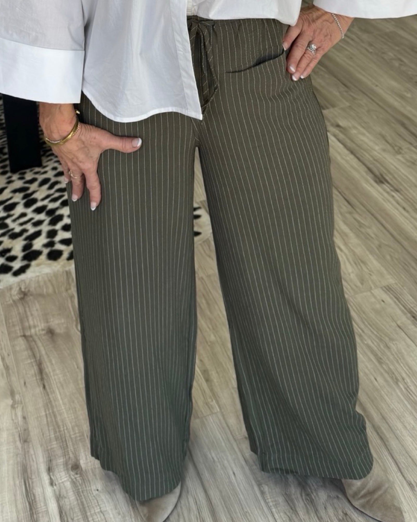 Stripe Olive pants are focus point of image. Lady is modeling showing off the latest fall fashion for women for online boutique