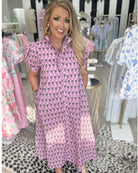 Woman wearing a pink patterned dress in a Boutique.